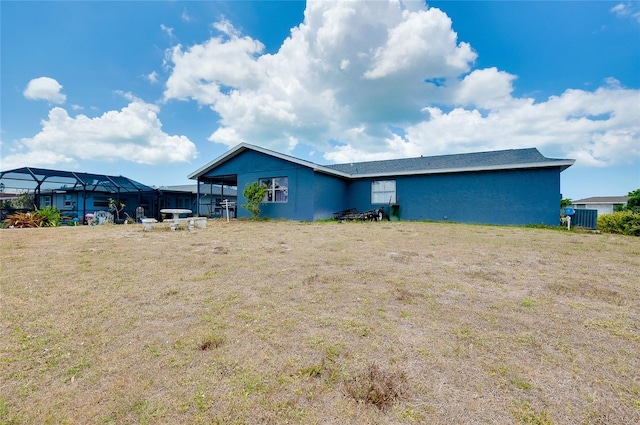 back of property with a yard and stucco siding