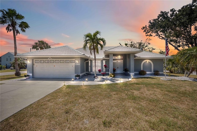 1568 Ringtail Rd, Venice, FL 34293 - mediterranean / spanish house featuring a garage, a tiled roof, stucco siding, and a yard