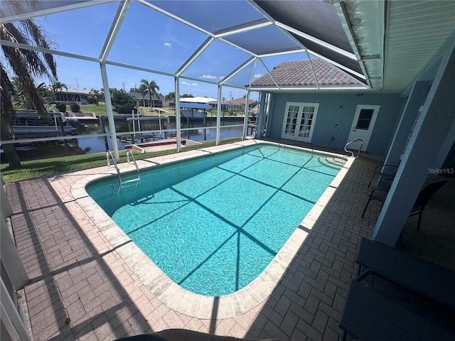 outdoor pool with a patio, a water view, a lanai, boat lift, and french doors