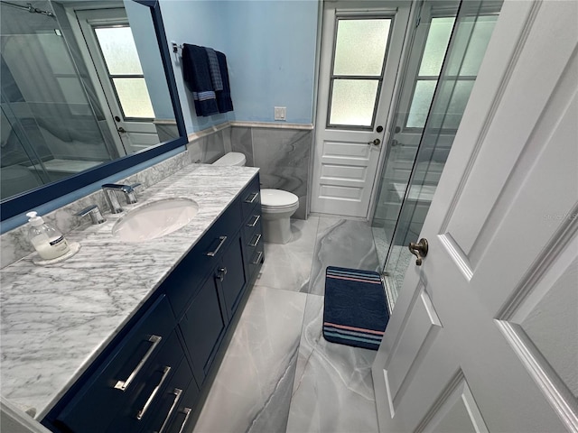 bathroom featuring tile walls, vanity, a stall shower, a wainscoted wall, and marble finish floor