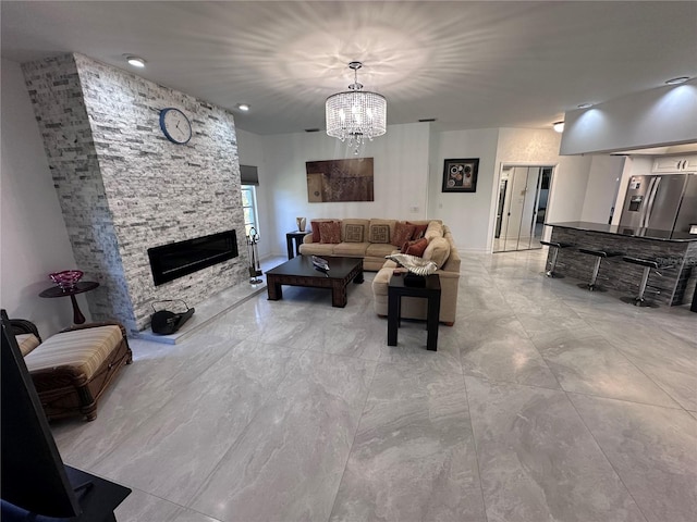 living room featuring an inviting chandelier and a stone fireplace