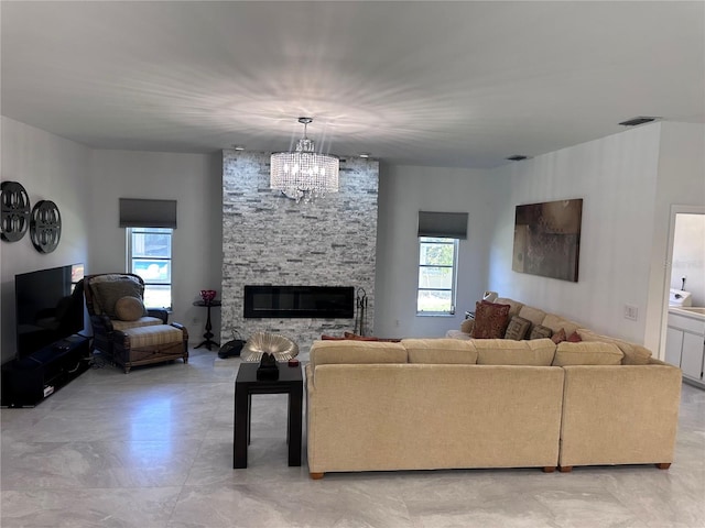 living room with an inviting chandelier, visible vents, a healthy amount of sunlight, and a fireplace