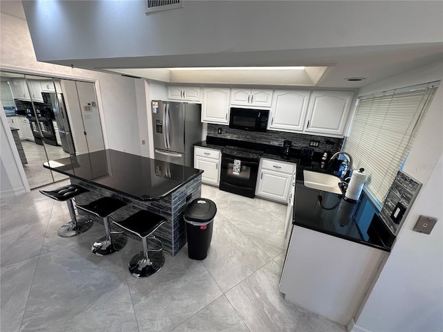 kitchen featuring decorative backsplash, white cabinets, a sink, dark countertops, and black appliances