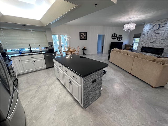 kitchen with a sink, dark countertops, stainless steel dishwasher, and an inviting chandelier