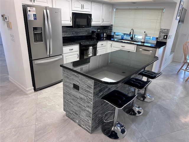 kitchen featuring black appliances, a sink, dark countertops, and baseboards