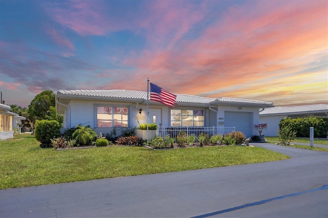 ranch-style home featuring an attached garage, a yard, driveway, and stucco siding