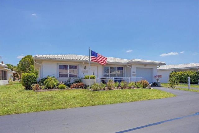 ranch-style home featuring an attached garage, aphalt driveway, stucco siding, and a front yard