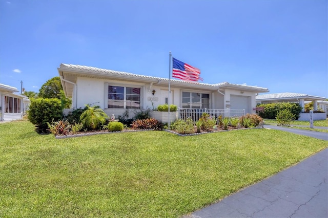 single story home with a tiled roof, an attached garage, a front yard, and stucco siding