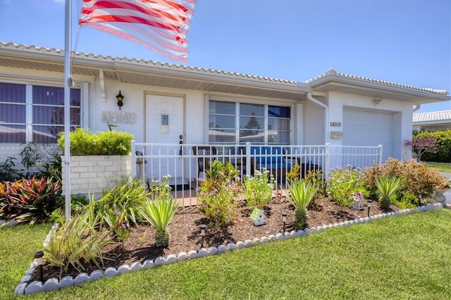 view of front facade with covered porch, an attached garage, and stucco siding