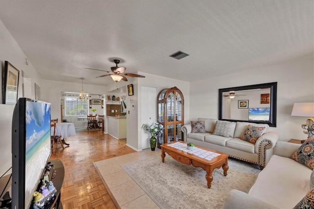 living room with a textured ceiling, ceiling fan, visible vents, and baseboards