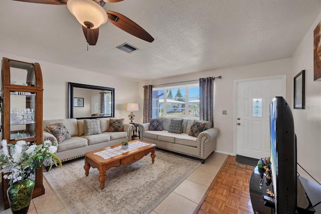 living area with visible vents, a textured ceiling, and ceiling fan