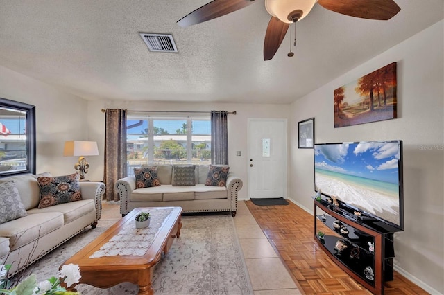 living room with visible vents, a textured ceiling, baseboards, and ceiling fan
