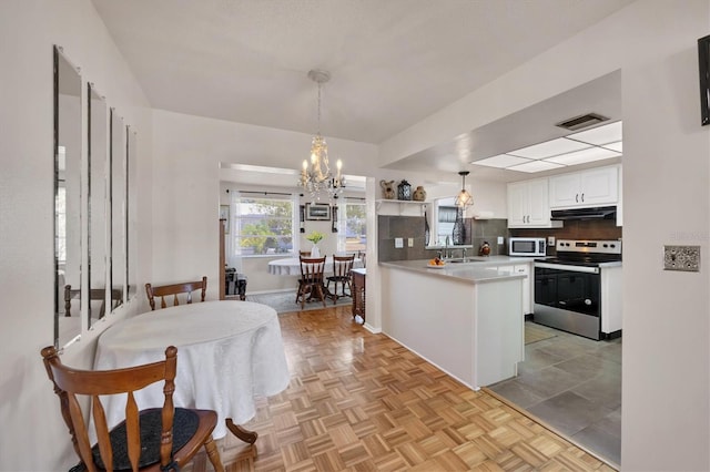 kitchen with a notable chandelier, stainless steel range with electric stovetop, white cabinetry, white microwave, and visible vents
