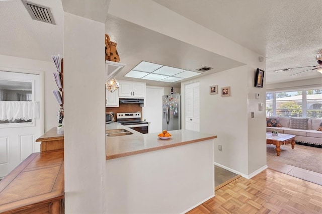kitchen with under cabinet range hood, visible vents, stainless steel fridge, and electric stove