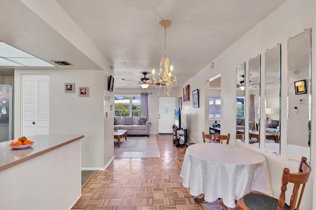 dining room with baseboards, visible vents, and ceiling fan with notable chandelier