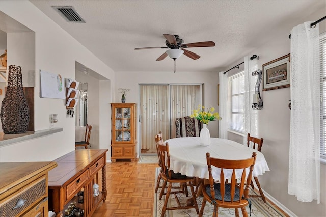dining space with visible vents, a textured ceiling, and ceiling fan