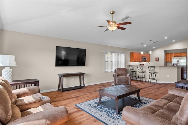 living room with visible vents, light wood-style flooring, ceiling fan, and vaulted ceiling