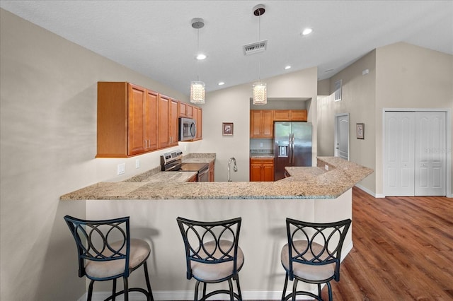 kitchen featuring brown cabinets, dark wood-style flooring, stainless steel appliances, lofted ceiling, and visible vents