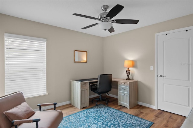 home office featuring baseboards, plenty of natural light, light wood finished floors, and ceiling fan