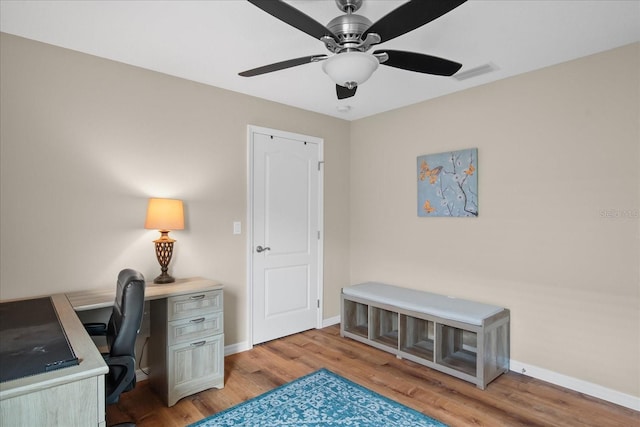 office space with a ceiling fan, baseboards, visible vents, and light wood-type flooring