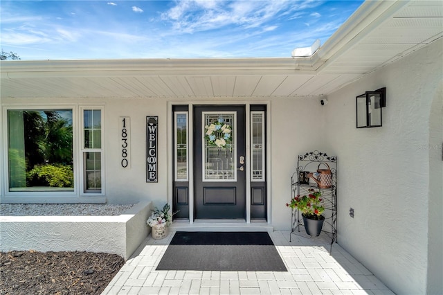 property entrance with a porch and stucco siding