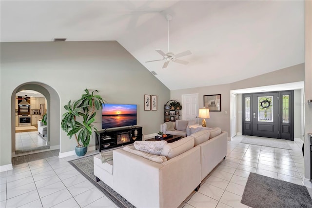 living area with light tile patterned floors, high vaulted ceiling, a ceiling fan, visible vents, and arched walkways