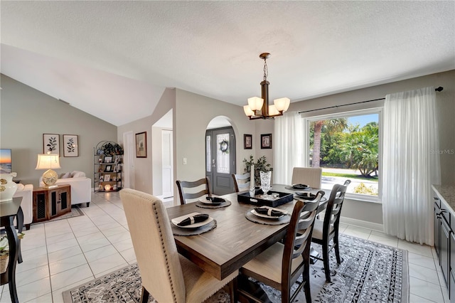 dining space with arched walkways, a notable chandelier, a textured ceiling, and light tile patterned flooring