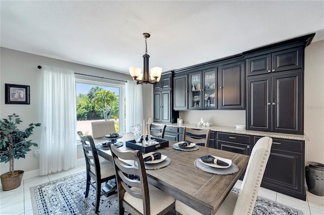 dining area with light tile patterned floors, a notable chandelier, and baseboards
