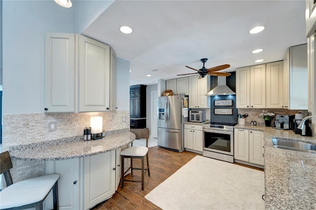 kitchen featuring tasteful backsplash, appliances with stainless steel finishes, wall chimney range hood, and a sink