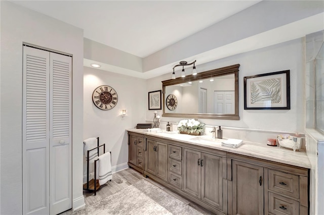 full bathroom featuring double vanity, a sink, wood finished floors, and a closet