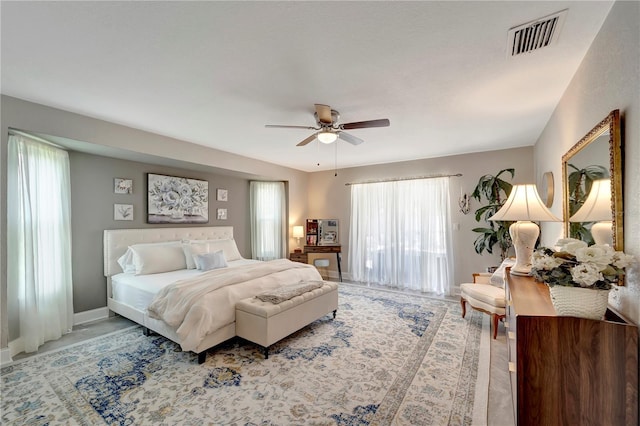 bedroom with baseboards, visible vents, ceiling fan, and multiple windows