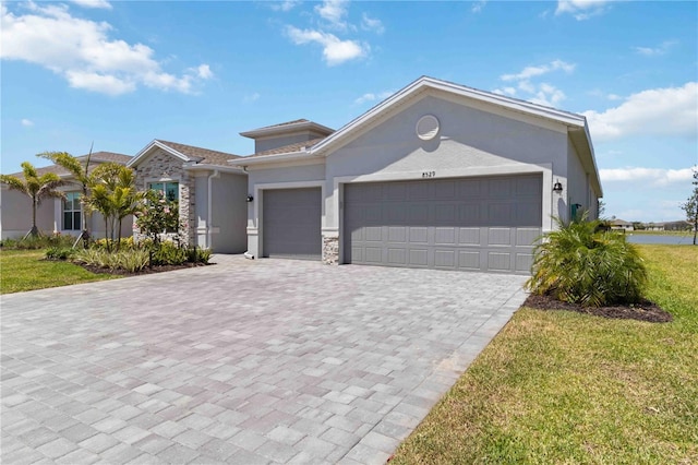 view of front facade with a front lawn, stone siding, decorative driveway, stucco siding, and an attached garage