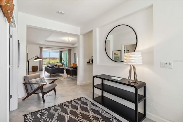 corridor featuring light tile patterned flooring, baseboards, and visible vents