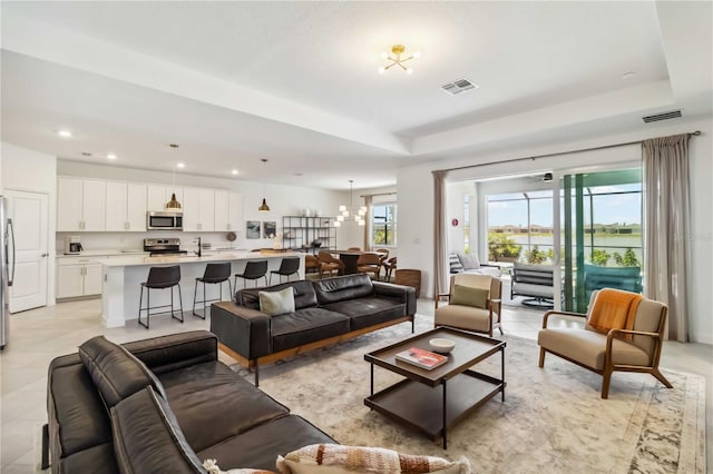 living room featuring recessed lighting, a tray ceiling, and visible vents