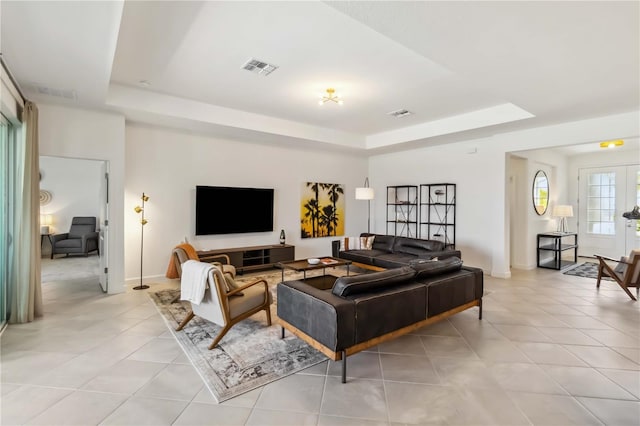 living area with light tile patterned floors, a raised ceiling, baseboards, and visible vents