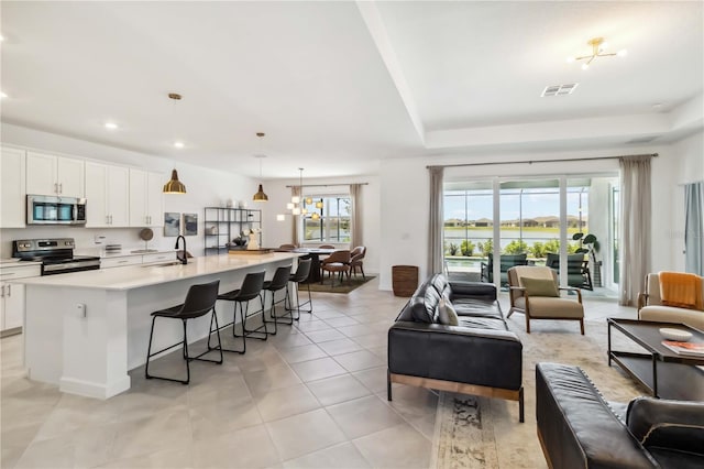 living area featuring recessed lighting, visible vents, light tile patterned floors, and a raised ceiling