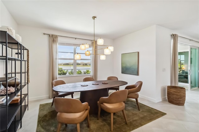 dining space featuring a water view, baseboards, a notable chandelier, and light tile patterned flooring
