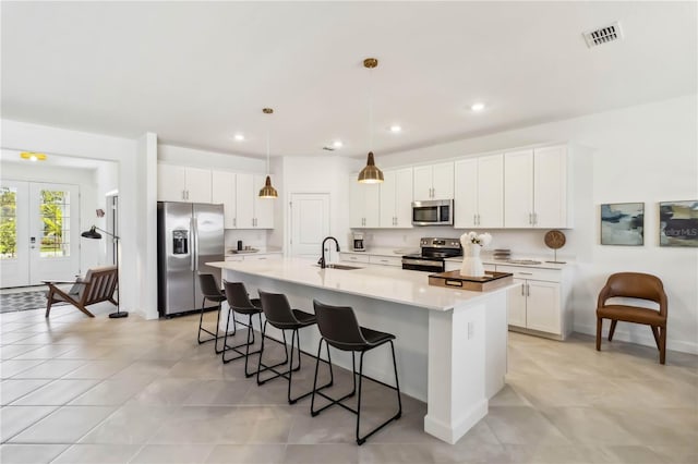 kitchen featuring appliances with stainless steel finishes, a sink, a kitchen breakfast bar, visible vents, and a center island with sink
