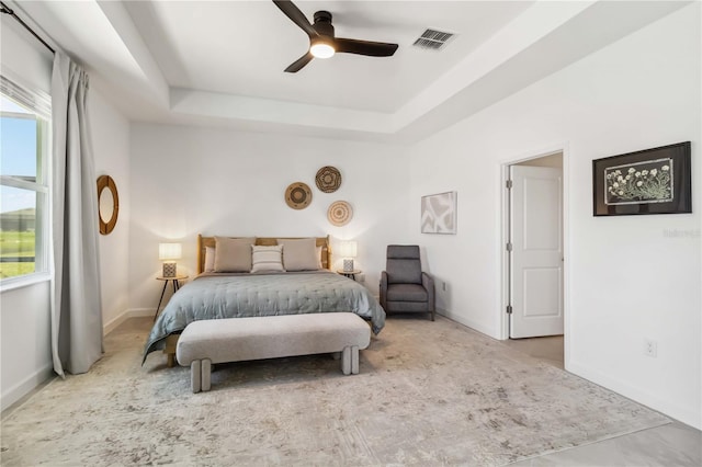 bedroom featuring baseboards, multiple windows, a tray ceiling, and visible vents