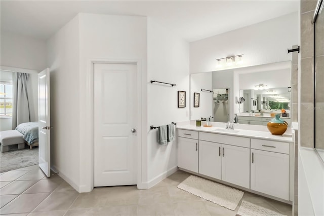 ensuite bathroom with tile patterned flooring, connected bathroom, baseboards, and vanity