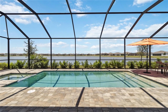 view of swimming pool with glass enclosure, a water view, a pool with connected hot tub, and a patio area