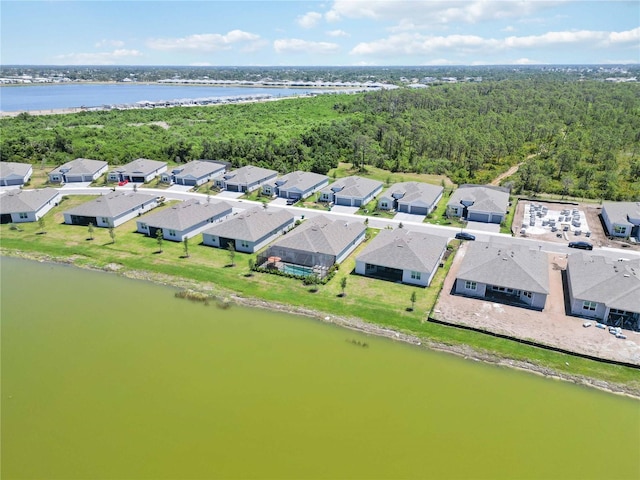 drone / aerial view featuring a water view, a residential view, and a wooded view