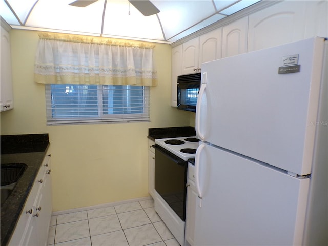 kitchen featuring white cabinets, black microwave, electric stove, freestanding refrigerator, and baseboards