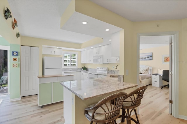 819 Montrose Dr Unit 102, Venice, FL 34293 - kitchen featuring light wood-style floors, a sink, white cabinetry, and white appliances