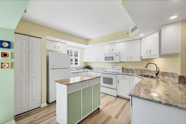 819 Montrose Dr Unit 102, Venice, FL 34293 - kitchen featuring a kitchen island, white appliances, light wood-style floors, white cabinetry, and a sink