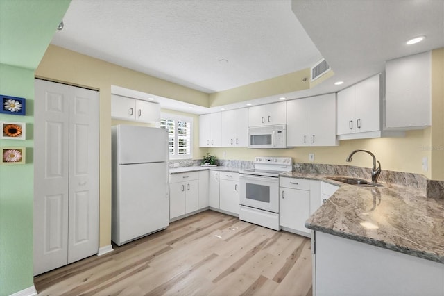 819 Montrose Dr Unit 102, Venice, FL 34293 - kitchen featuring a sink, white cabinets, light wood-type flooring, and white appliances