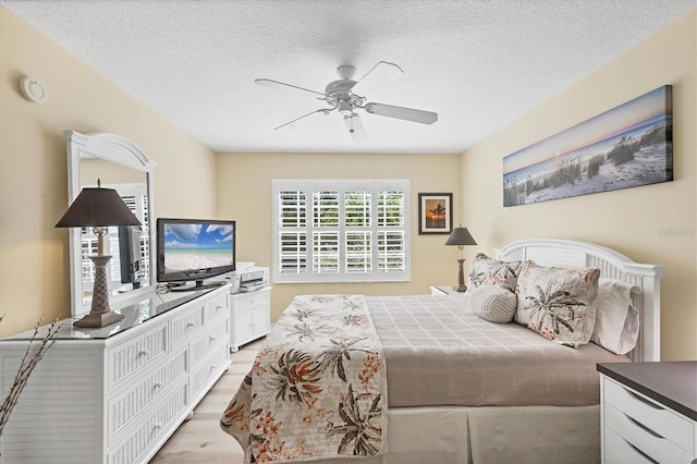 819 Montrose Dr Unit 102, Venice, FL 34293 - bedroom featuring a textured ceiling, a ceiling fan, and light wood-style flooring