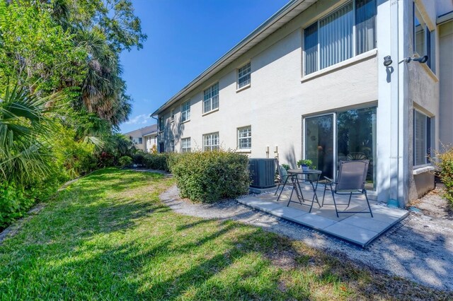 819 Montrose Dr Unit 102, Venice, FL 34293 - rear view of property featuring a lawn, a patio area, stucco siding, and central air condition unit