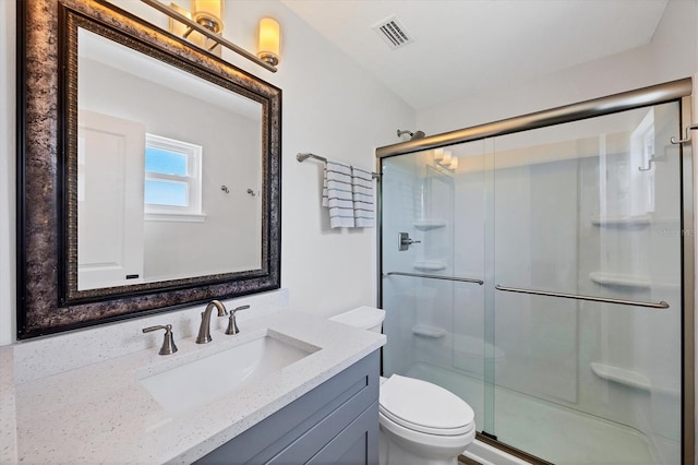 bathroom featuring vanity, a shower stall, toilet, and visible vents