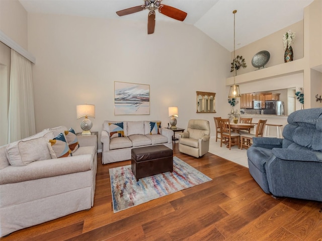 living room with ceiling fan, high vaulted ceiling, and wood finished floors